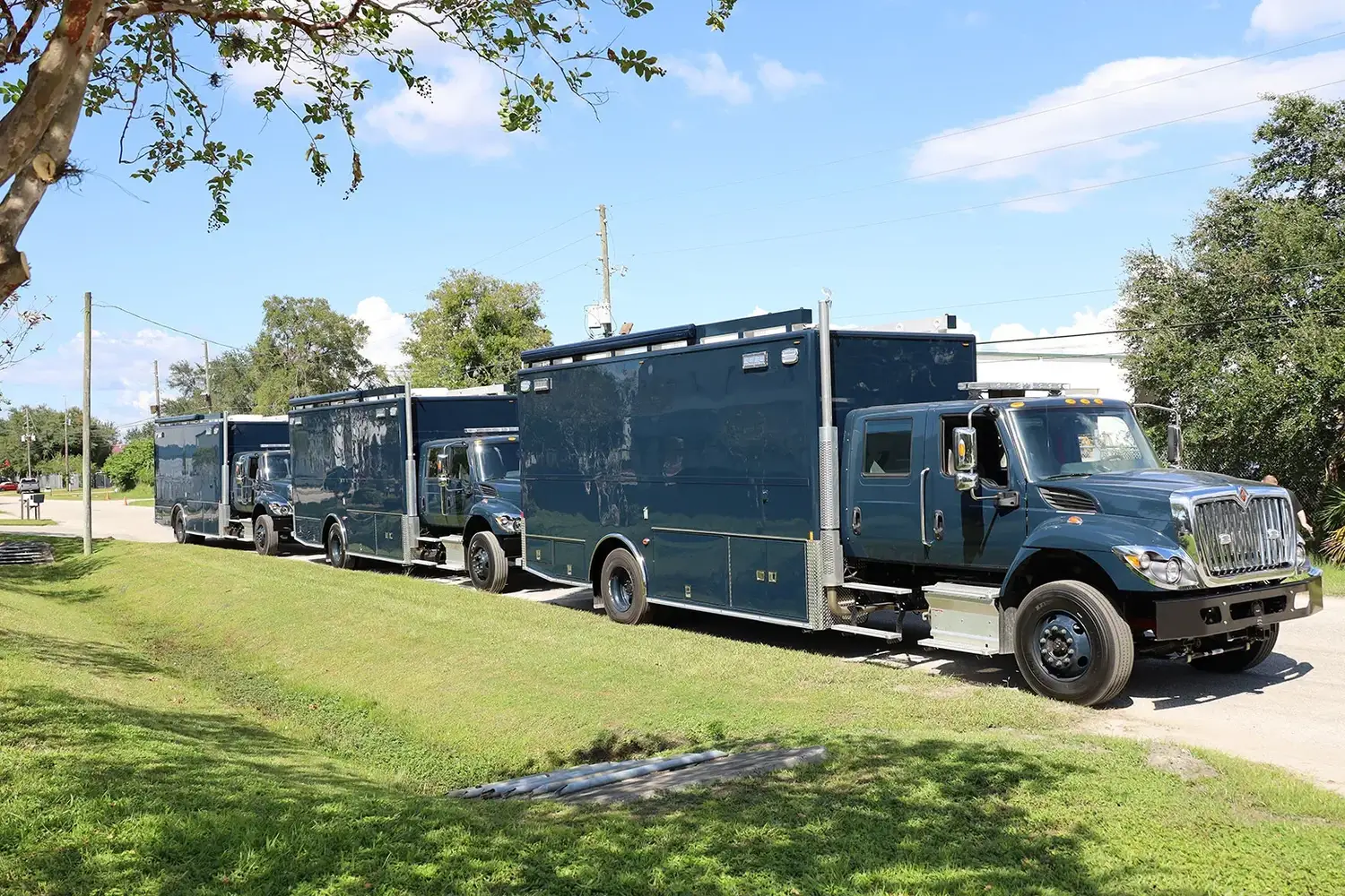 Three C-36 US Navy EOD Bomb units parked outside near the Frontline Communications building on a sunny day.
