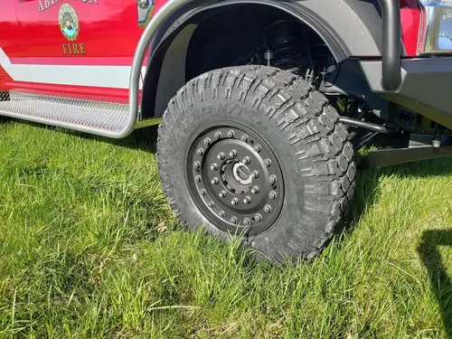 Exterior view of small fire truck showing cab, body compartments, and wheel/tire area.