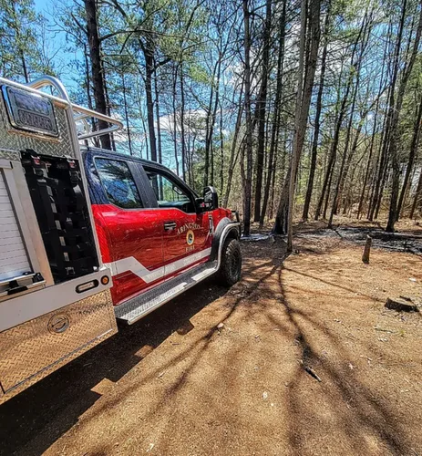 Exterior view of small fire truck showing cab, body compartments, and wheel/tire area.