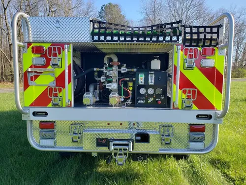 Exterior view of small fire truck showing cab, body compartments, and wheel/tire area.