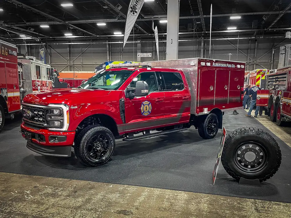 Front driver-side three-quarter view of red brush truck indoors.