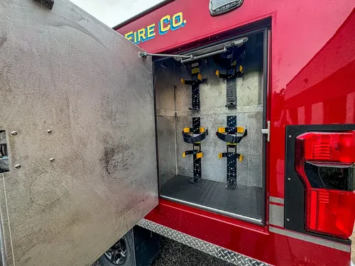 Open vertical compartment with mounted long-handled tools.