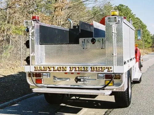 Exterior view of small fire truck showing cab, body compartments, and wheel/tire area.