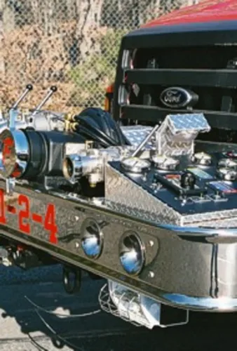 Exterior view of small fire truck showing cab, body compartments, and wheel/tire area.