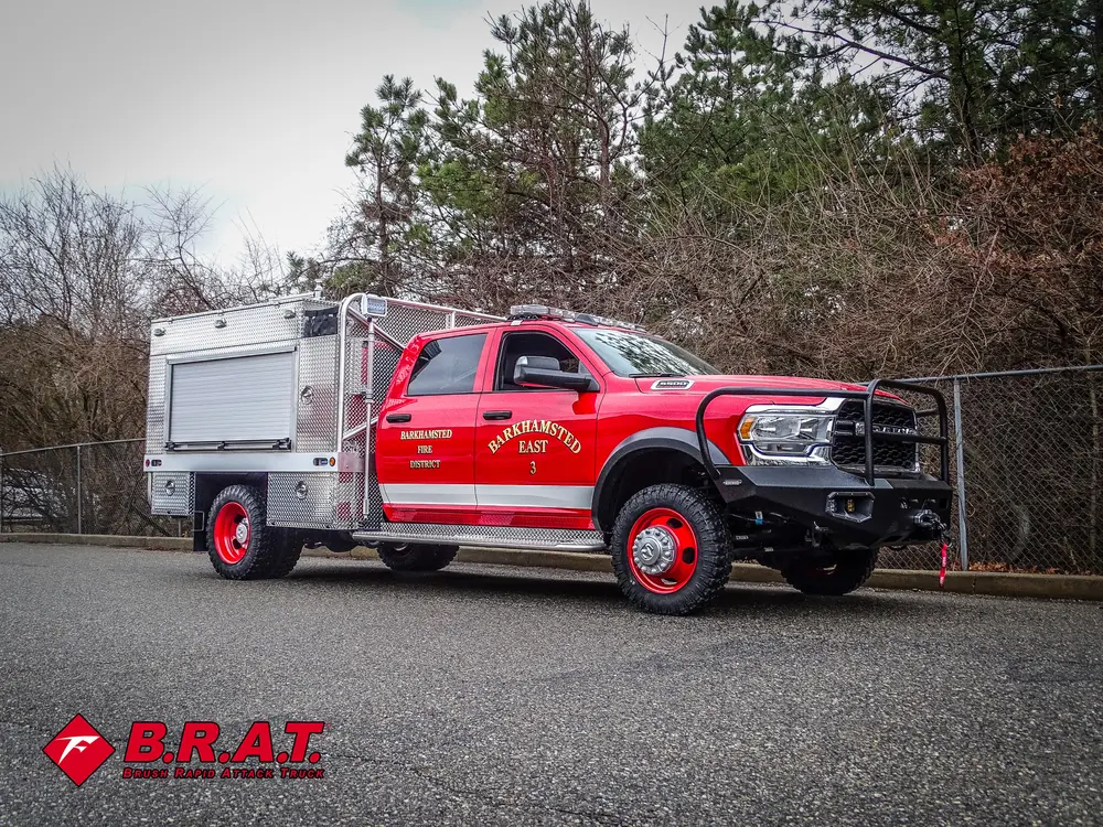 Driver-side front three-quarter view of red brush truck outdoors.
