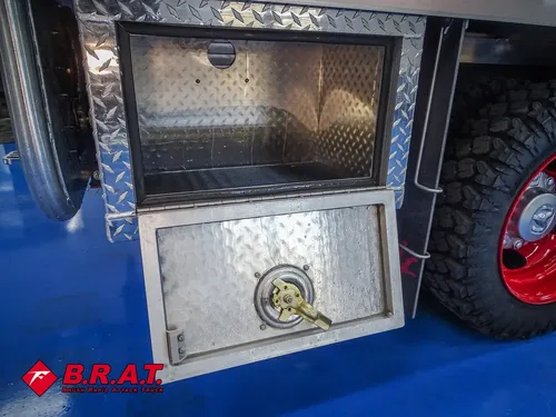 Open lower diamond-plate compartment beneath side body panel.