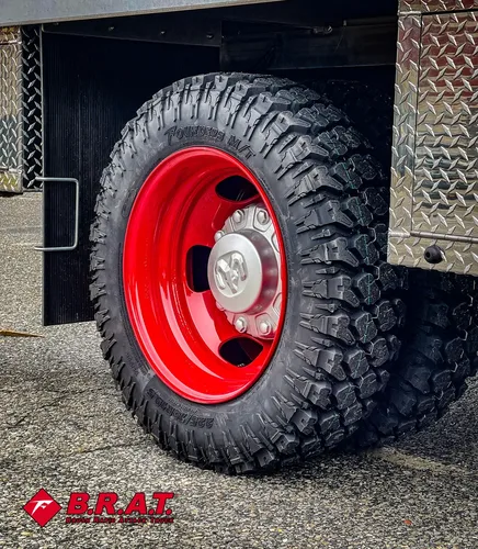 Second close-up of treaded tire and red wheel rim.