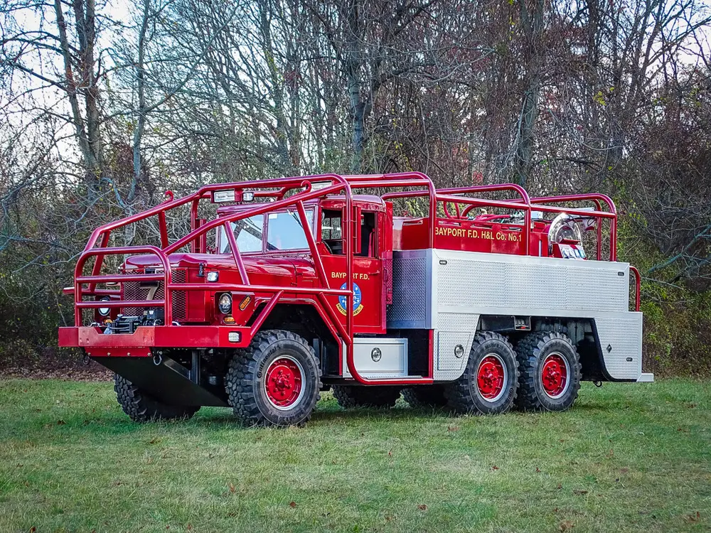Front-left three-quarter exterior view of the red six-wheel brush truck.