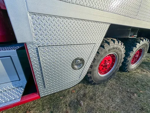 Diamond-plate side body and tandem rear wheel close-up.