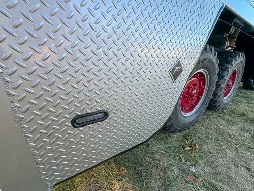 Diamond-plate side body close-up with flush latch on lower panel.