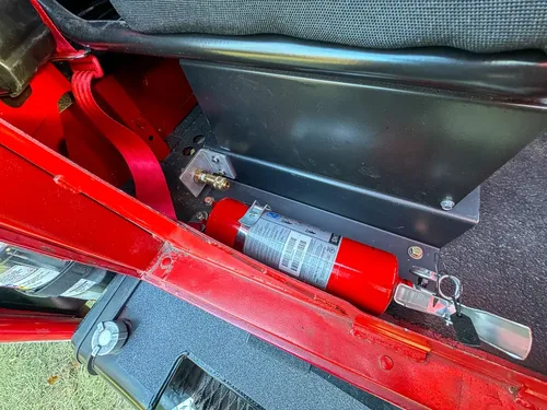 Interior side compartment under dashboard with mounted fire extinguisher.
