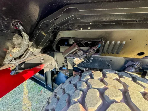 Front suspension and underbody close-up near the wheel.