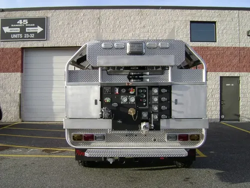 Exterior view of small fire truck showing cab, body compartments, and wheel/tire area.