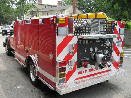 Exterior view of small fire truck showing cab, body compartments, and wheel/tire area.