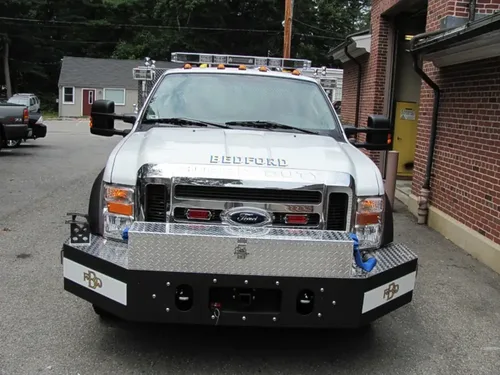 Exterior view of small fire truck showing cab, body compartments, and wheel/tire area.