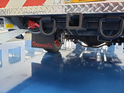 Exterior view of small fire truck showing cab, body compartments, and wheel/tire area.
