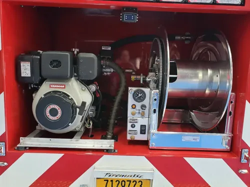 Exterior view of small fire truck showing cab, body compartments, and wheel/tire area.