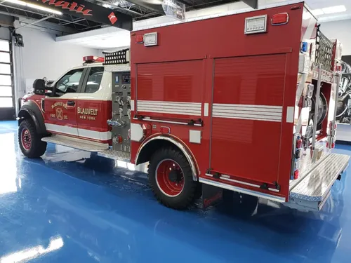 Exterior view of small fire truck showing cab, body compartments, and wheel/tire area.