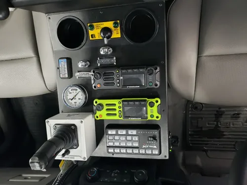 Exterior view of small fire truck showing cab, body compartments, and wheel/tire area.