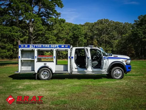 Exterior view of small fire truck showing cab, body compartments, and wheel/tire area.