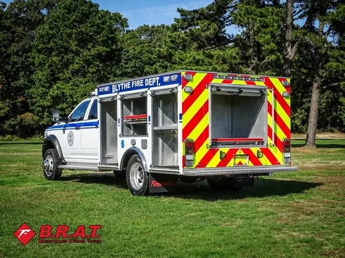 Exterior view of small fire truck showing cab, body compartments, and wheel/tire area.