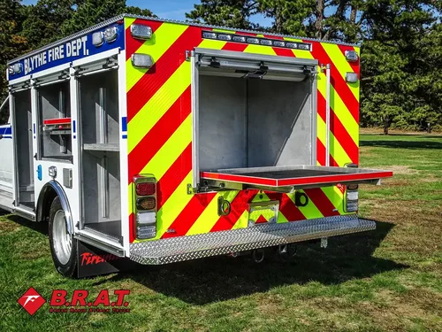 Exterior view of small fire truck showing cab, body compartments, and wheel/tire area.