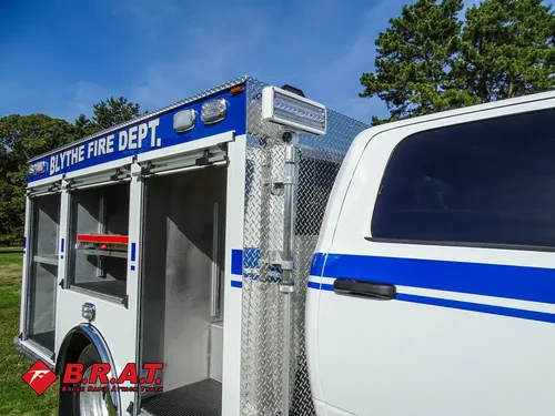 Exterior view of small fire truck showing cab, body compartments, and wheel/tire area.