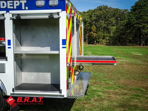 Exterior view of small fire truck showing cab, body compartments, and wheel/tire area.
