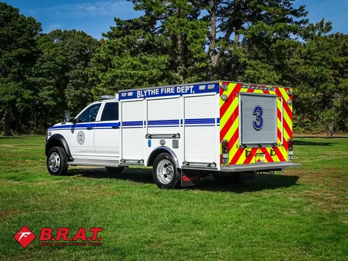 Exterior view of small fire truck showing cab, body compartments, and wheel/tire area.