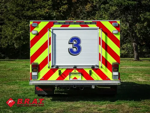 Exterior view of small fire truck showing cab, body compartments, and wheel/tire area.
