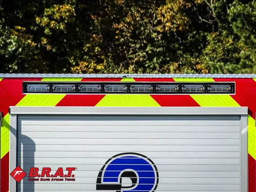 Exterior view of small fire truck showing cab, body compartments, and wheel/tire area.