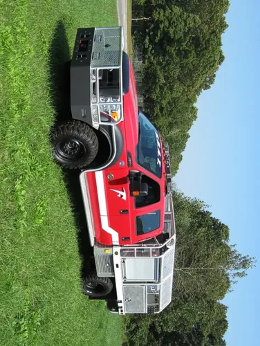 Exterior view of small fire truck showing cab, body compartments, and wheel/tire area.