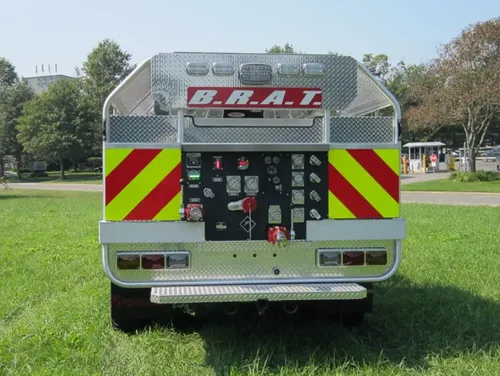 Exterior view of small fire truck showing cab, body compartments, and wheel/tire area.