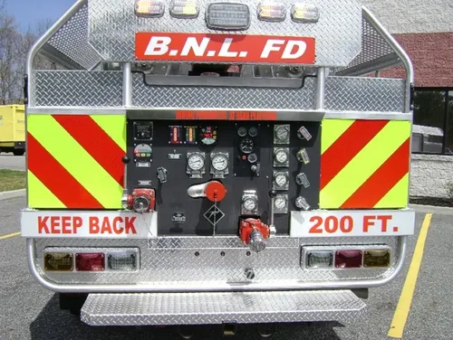 Exterior view of small fire truck showing cab, body compartments, and wheel/tire area.
