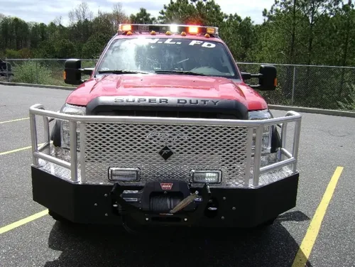 Exterior view of small fire truck showing cab, body compartments, and wheel/tire area.