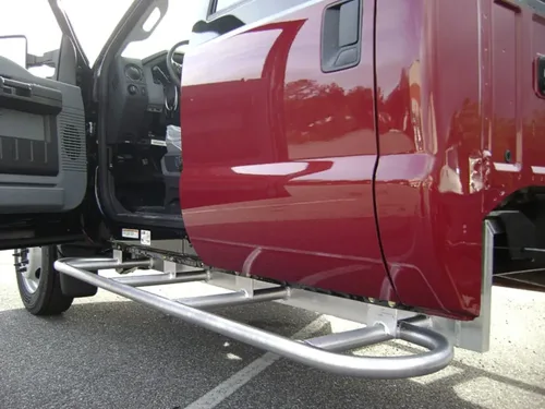 Exterior view of small fire truck showing cab, body compartments, and wheel/tire area.