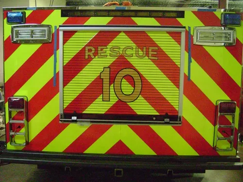 Exterior view of small fire truck showing cab, body compartments, and wheel/tire area.