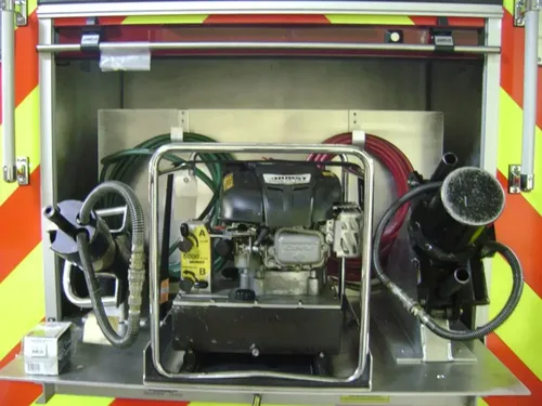 Exterior view of small fire truck showing cab, body compartments, and wheel/tire area.