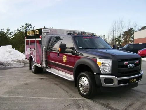 Exterior view of small fire truck showing cab, body compartments, and wheel/tire area.