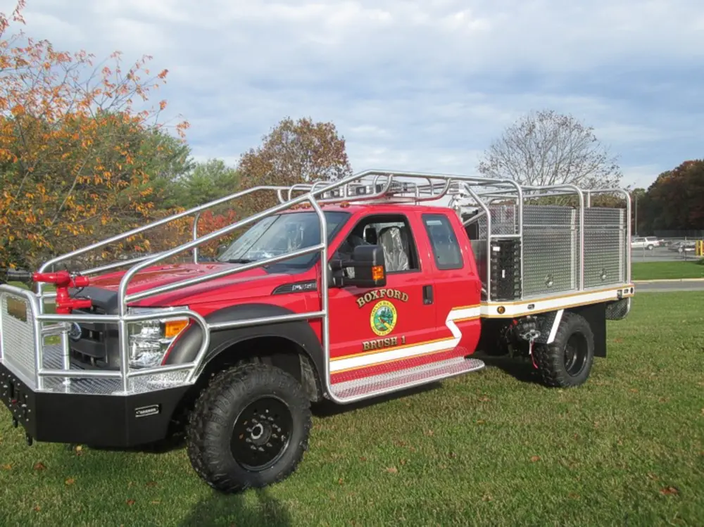 Exterior view of small fire truck showing cab, body compartments, and wheel/tire area.