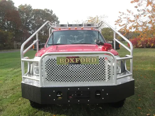 Exterior view of small fire truck showing cab, body compartments, and wheel/tire area.