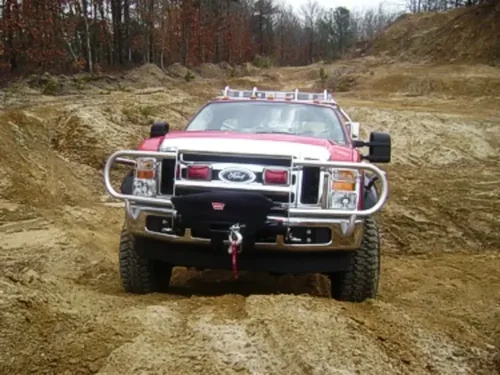 Exterior view of small fire truck showing cab, body compartments, and wheel/tire area.