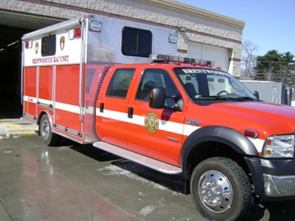 Front driver-side three-quarter view of red Brentwood rehab unit truck.