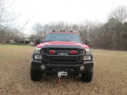 Exterior view of small fire truck showing cab, body compartments, and wheel/tire area.
