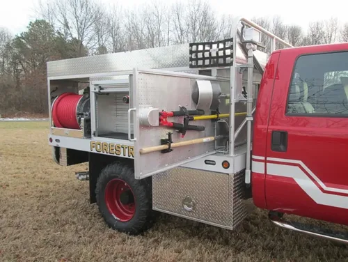 Exterior view of small fire truck showing cab, body compartments, and wheel/tire area.