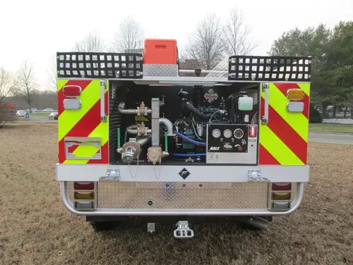 Exterior view of small fire truck showing cab, body compartments, and wheel/tire area.
