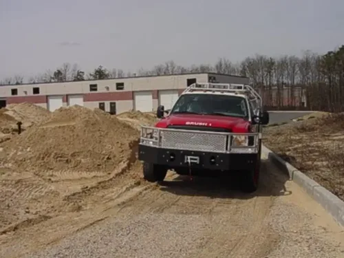 Exterior view of small fire truck showing cab, body compartments, and wheel/tire area.