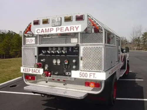 Exterior view of small fire truck showing cab, body compartments, and wheel/tire area.