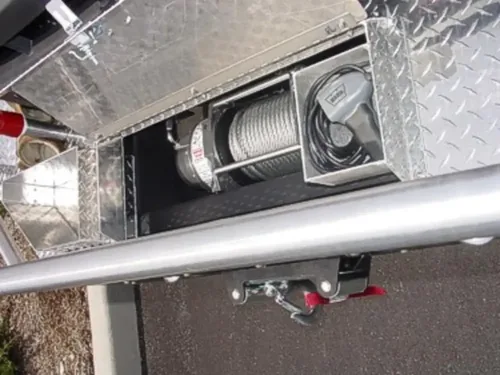 Exterior view of small fire truck showing cab, body compartments, and wheel/tire area.