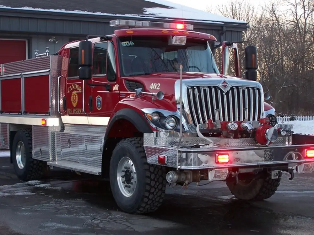 Exterior view of small fire truck showing cab, body compartments, and wheel/tire area.